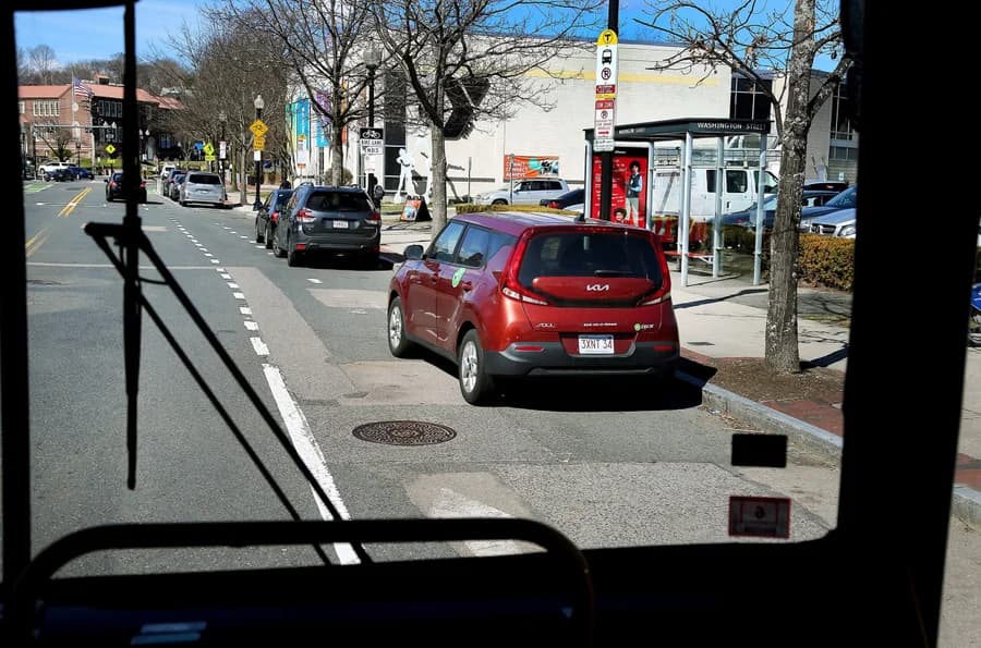 Red car stopped beside a bus stop, viewed from a bus